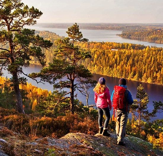Twee wandelaars kijken uit over Zweedse meren en herfstbossen